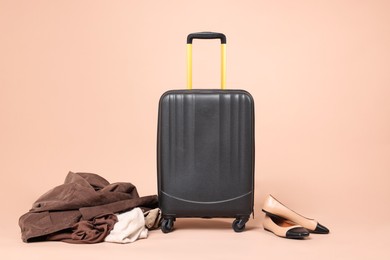 Photo of Suitcase, shoes and messy pile of clothes on beige background