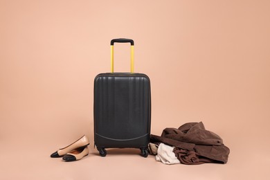Photo of Suitcase, shoes and messy pile of clothes on beige background