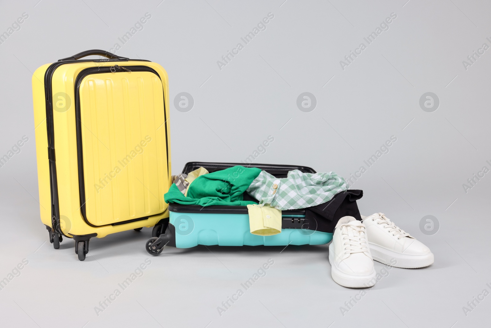 Photo of Suitcases with messy clothes and shoes on light background