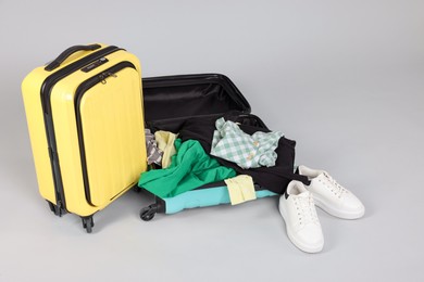 Photo of Suitcases with messy clothes and shoes on light background