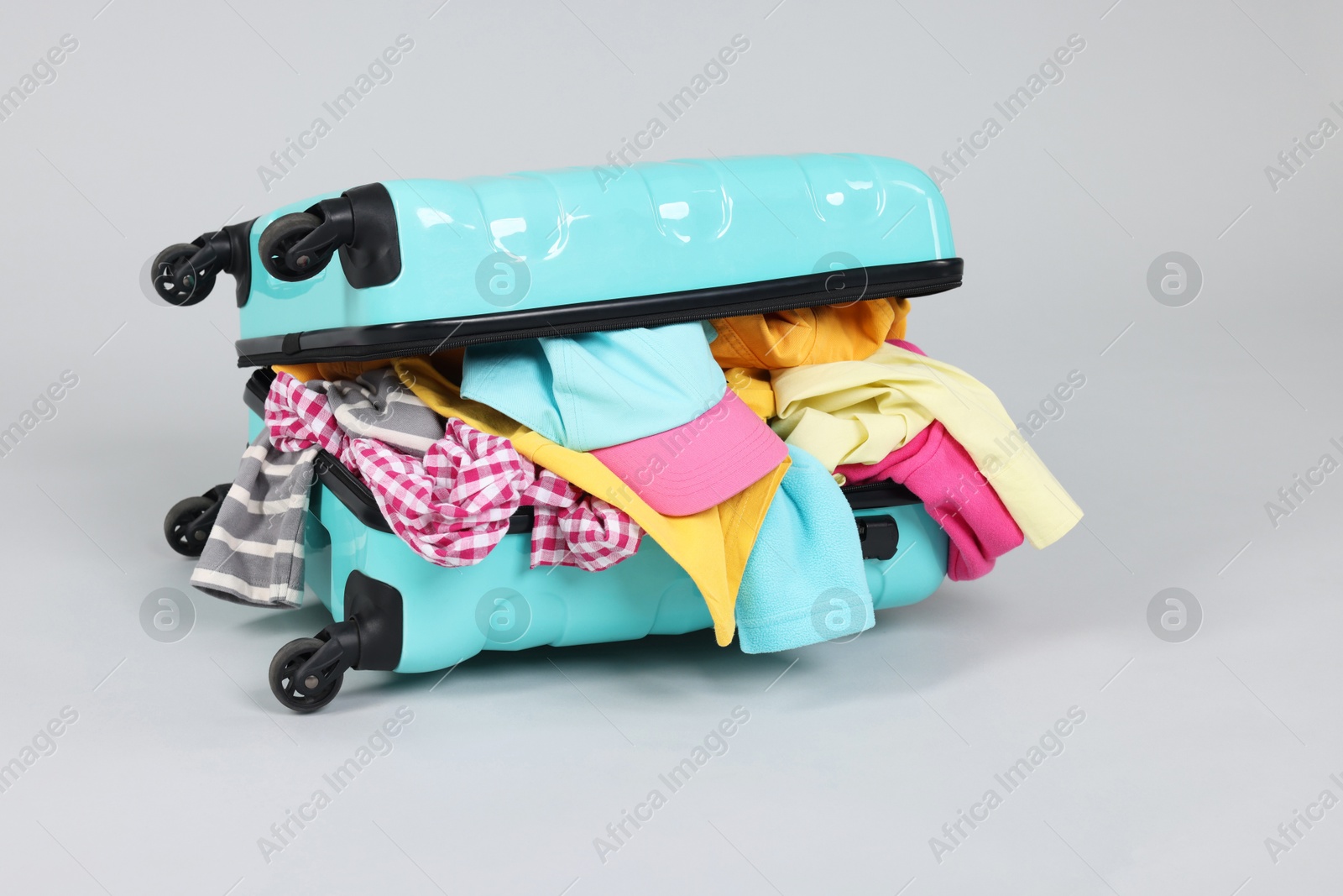 Photo of Packed suitcase full of clothes on light grey background