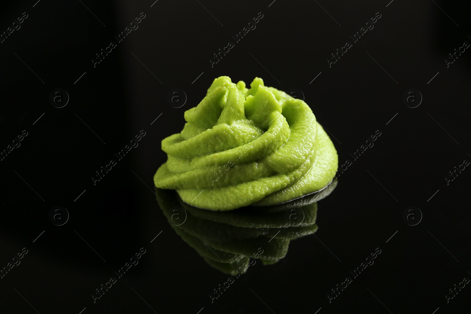 Photo of Hot wasabi paste on black mirror surface, closeup