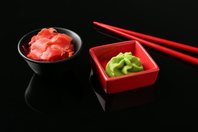 Photo of Hot wasabi paste, ginger and chopsticks on black mirror surface, closeup