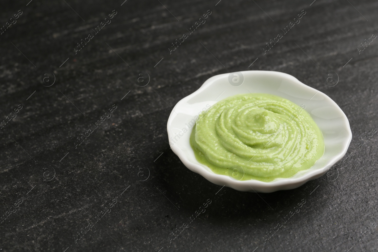 Photo of Hot wasabi paste on dark textured table, closeup. Space for text