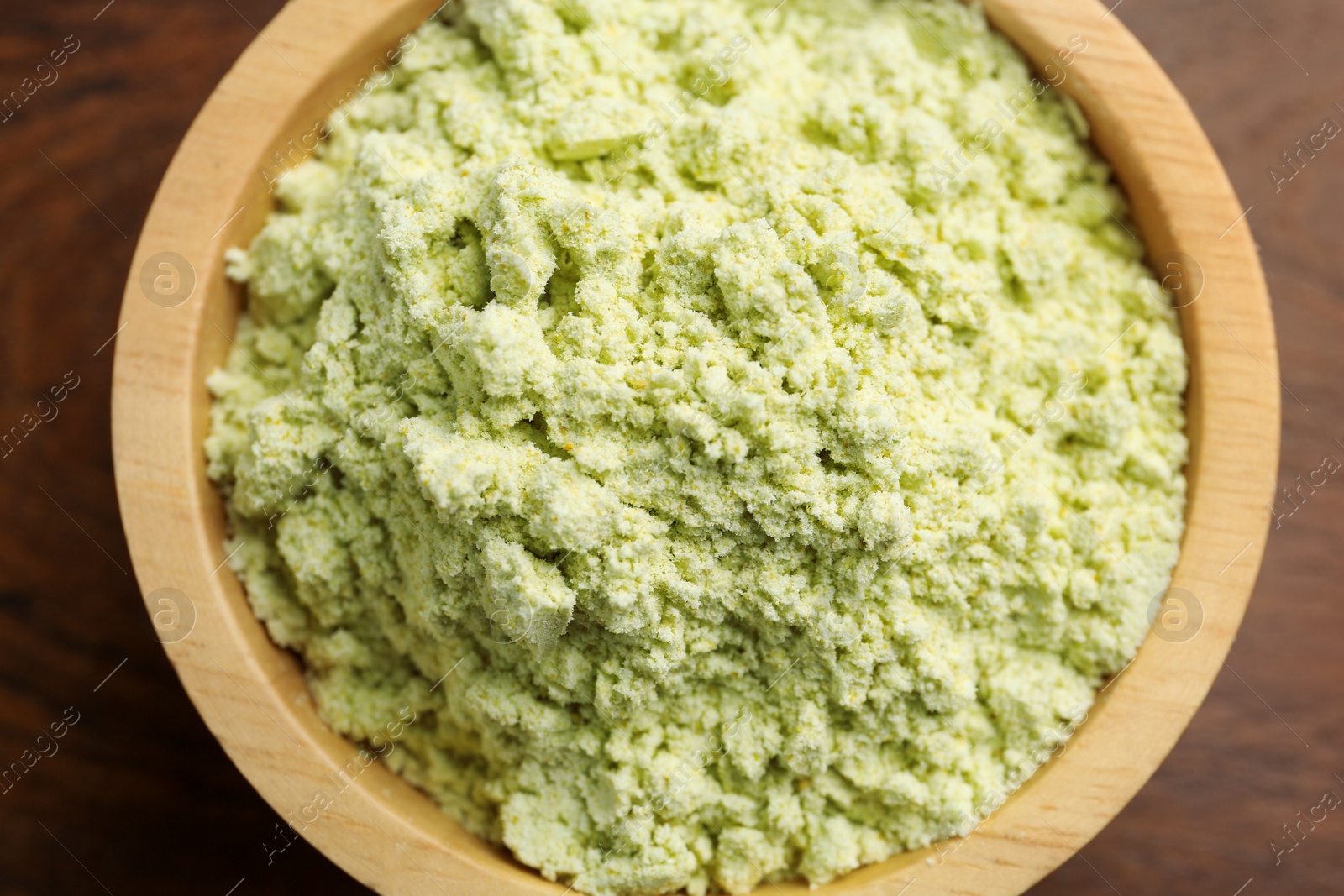 Photo of Dry wasabi powder in bowl on wooden table, top view