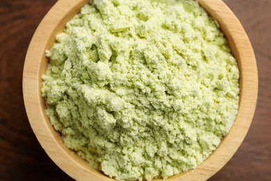 Photo of Dry wasabi powder in bowl on wooden table, top view