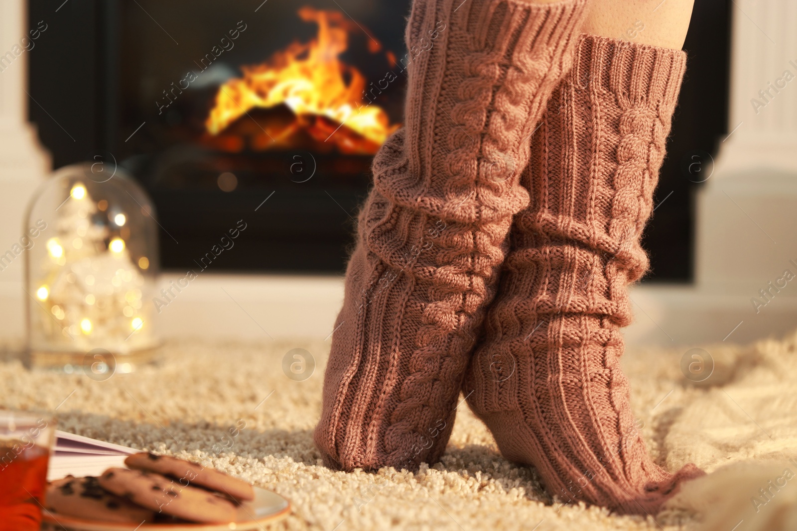 Photo of Woman wearing knitted socks at home, closeup