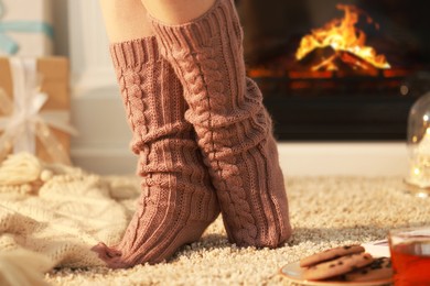 Photo of Woman wearing knitted socks at home, closeup