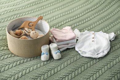 Photo of Baby clothes and box with toys on green blanket