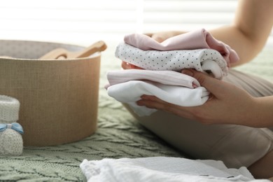 Photo of Woman with baby clothes on bed at home, closeup