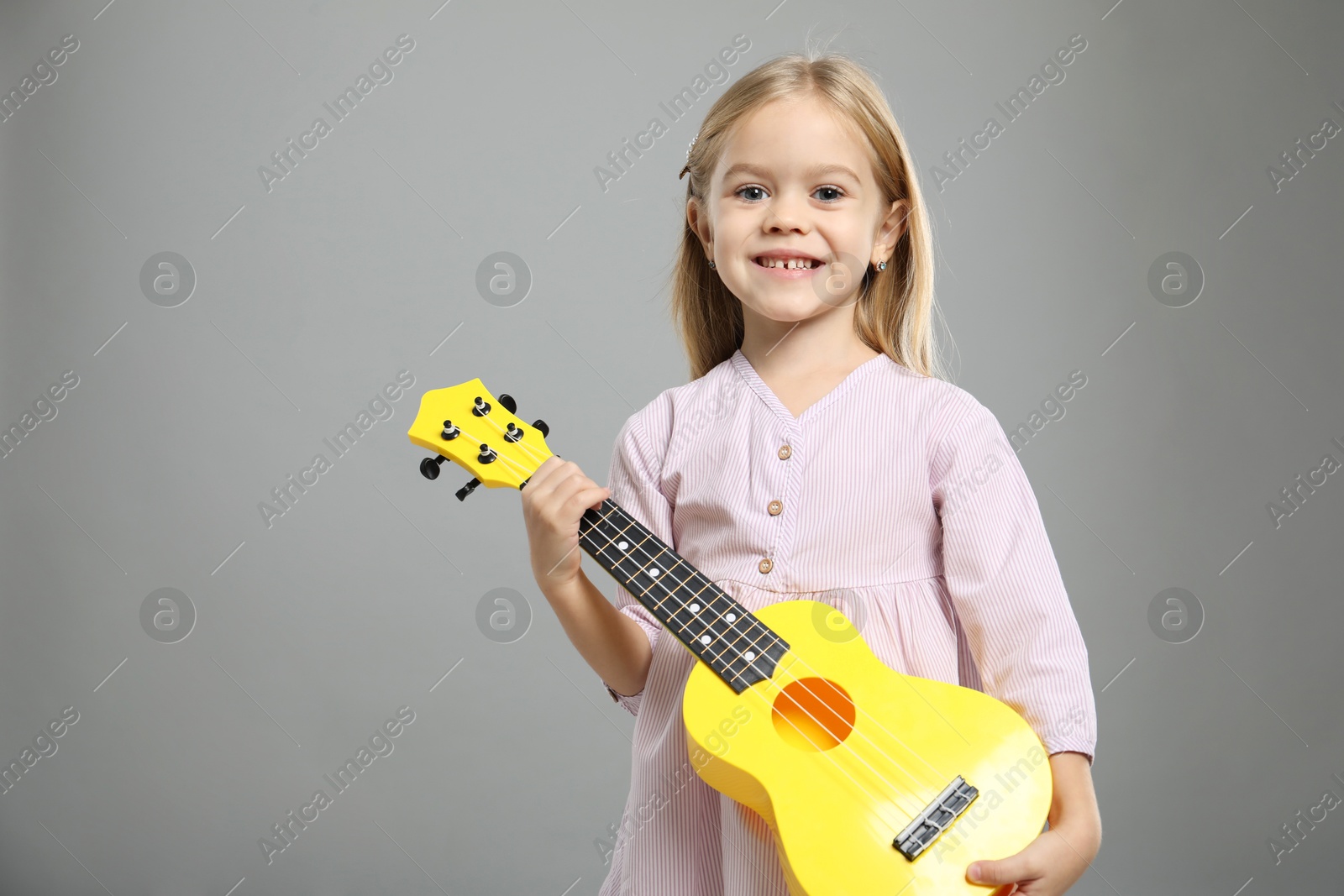 Photo of Little girl with ukulele on gray background