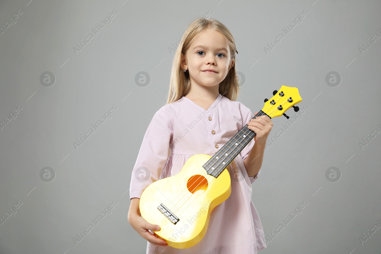 Photo of Little girl with ukulele on gray background