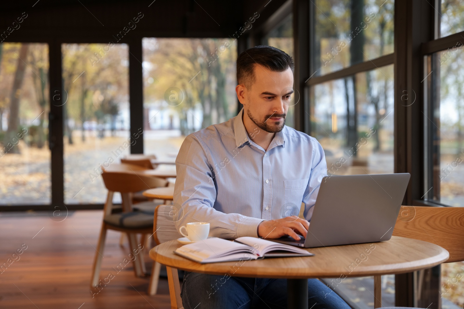 Photo of Man working on laptop at table in cafe, space for text