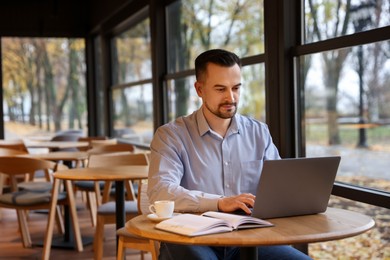 Photo of Man working on laptop at table in cafe, space for text