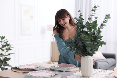 Woman setting table for dinner at home, space for text