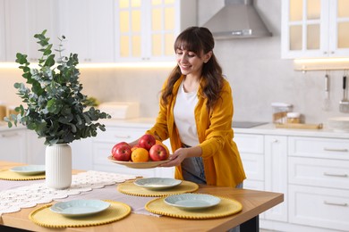 Woman setting table for dinner at home