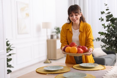 Photo of Woman setting table for dinner at home, space for text