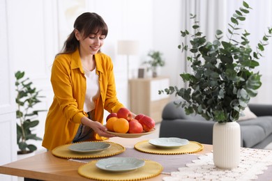 Photo of Woman setting table for dinner at home