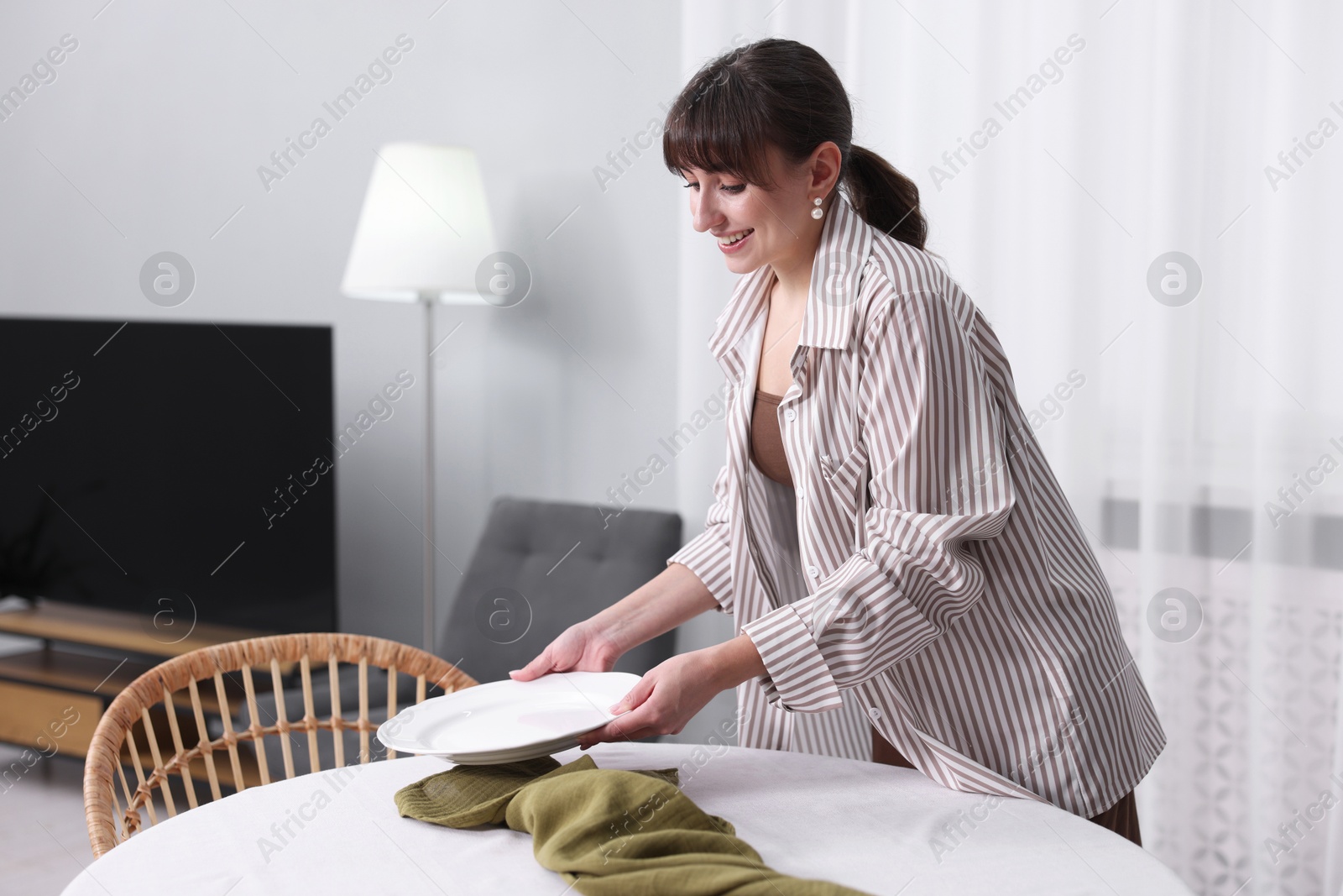 Photo of Woman setting table for dinner at home