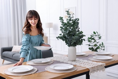 Woman setting table for dinner at home