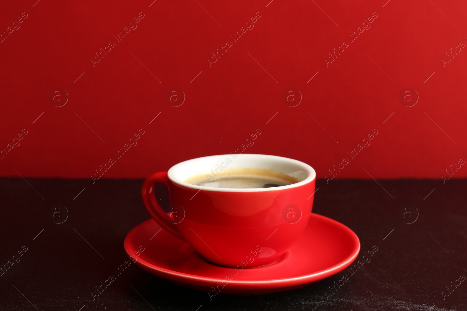 Red cup with coffee on black table Photo of Red cup with coffee on black table