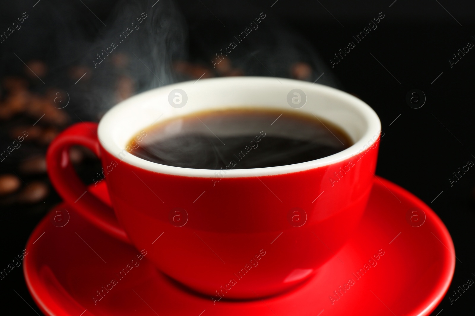 Red cup with coffee and roasted beans on black background, closeup Photo of Red cup with coffee and roasted beans on black background, closeup