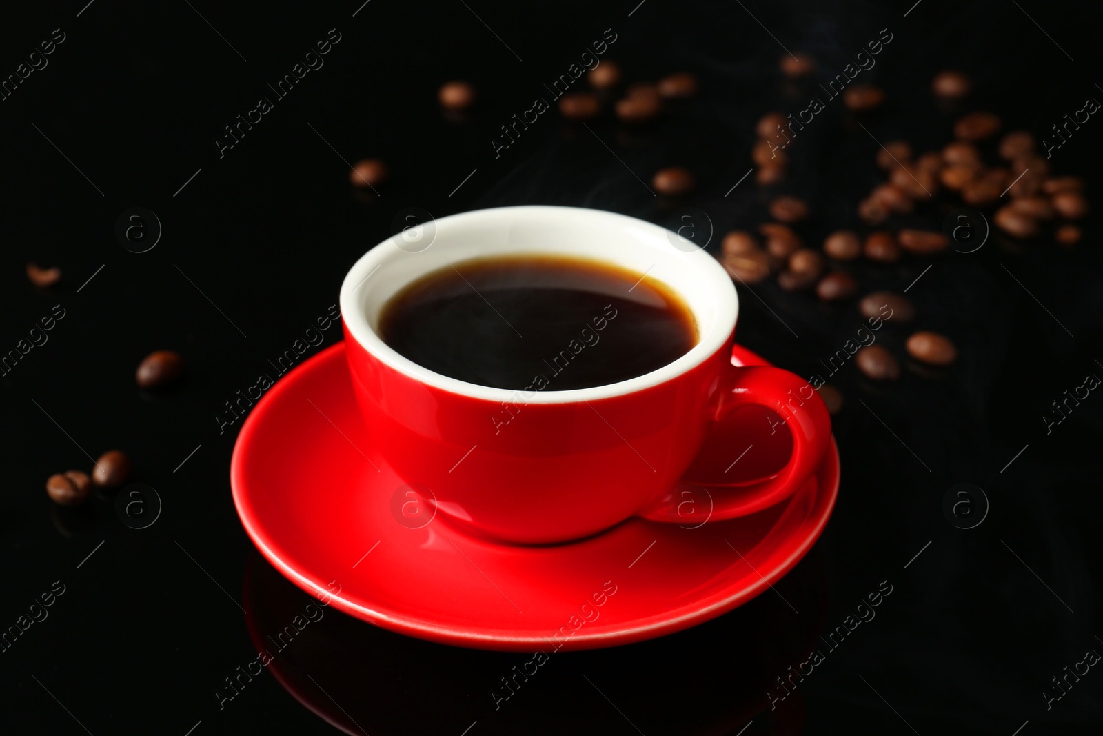 Red cup with coffee and roasted beans on black background Photo of Red cup with coffee and roasted beans on black background