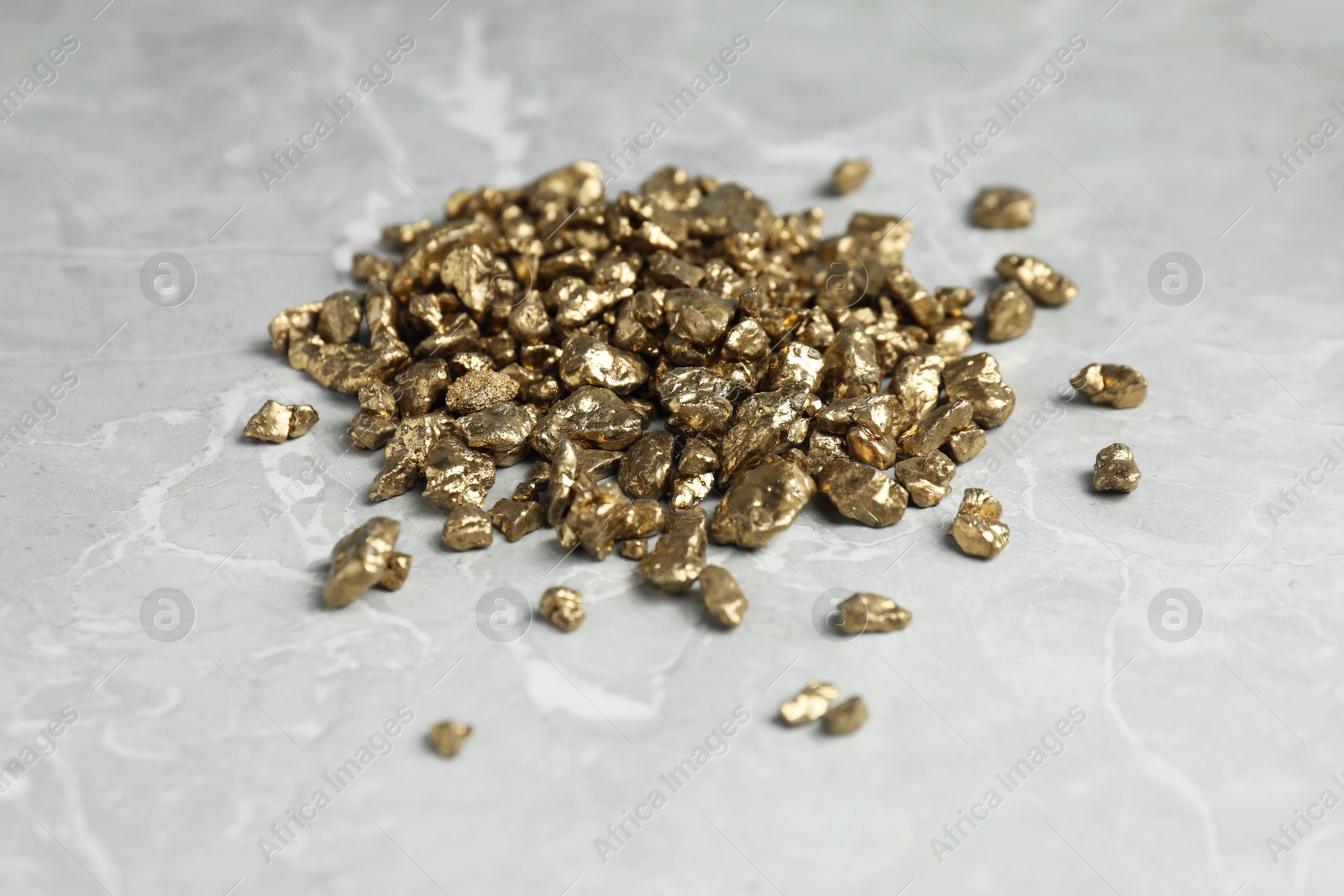 Photo of Gold nuggets on grey marble table, closeup