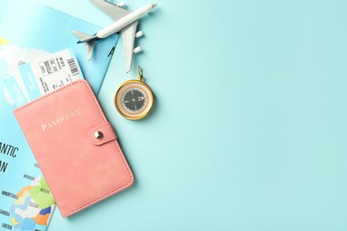 Photo of Passport with tickets, plane model, map and compass on light blue background, flat lay. Space for text