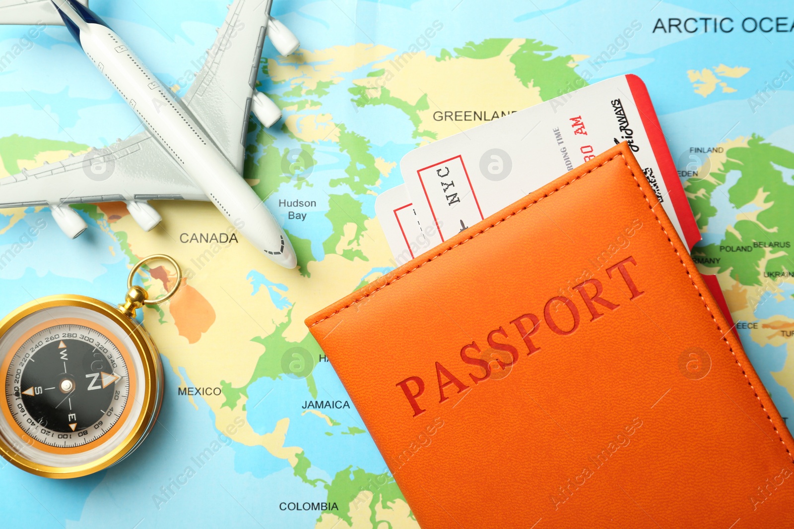 Photo of Passport with tickets, compass and plane model on world map, flat lay