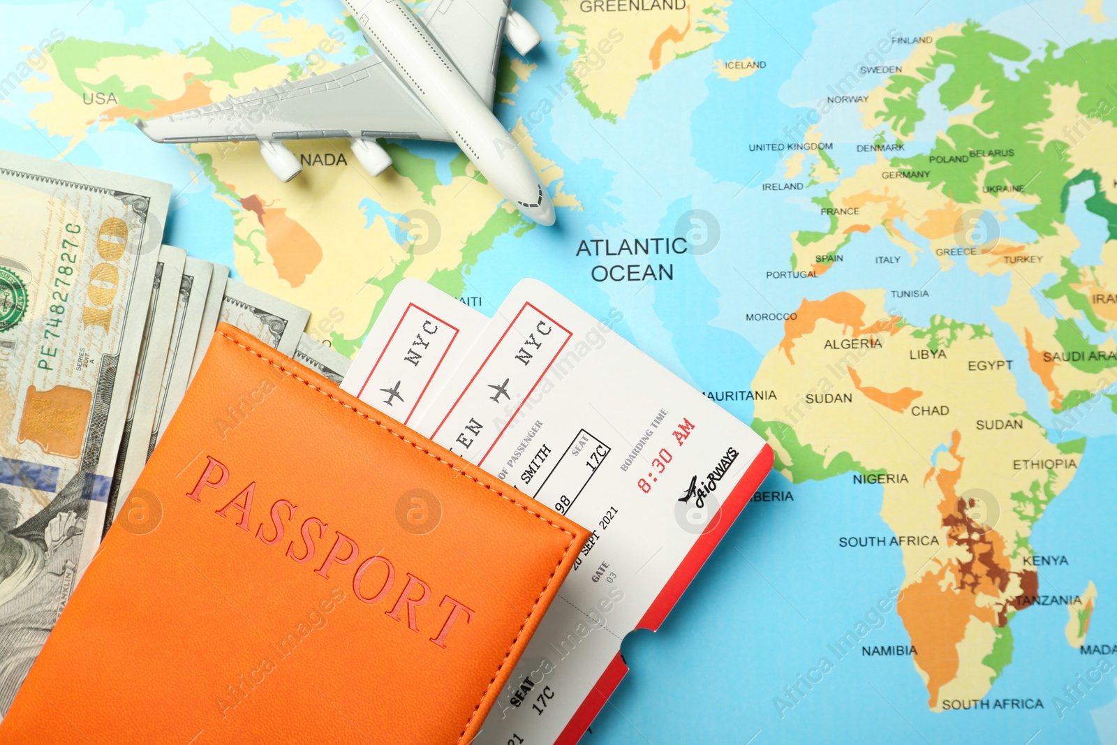 Photo of Passport with tickets, money and plane model on world map, flat lay