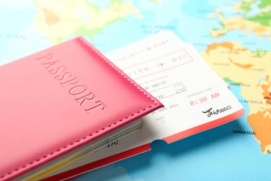 Photo of Passport in pink cover and flight tickets on world map, closeup