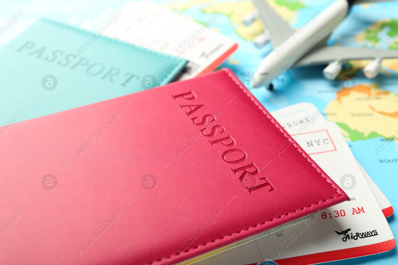 Photo of Passports in color covers, flight tickets and plane model on world map, closeup