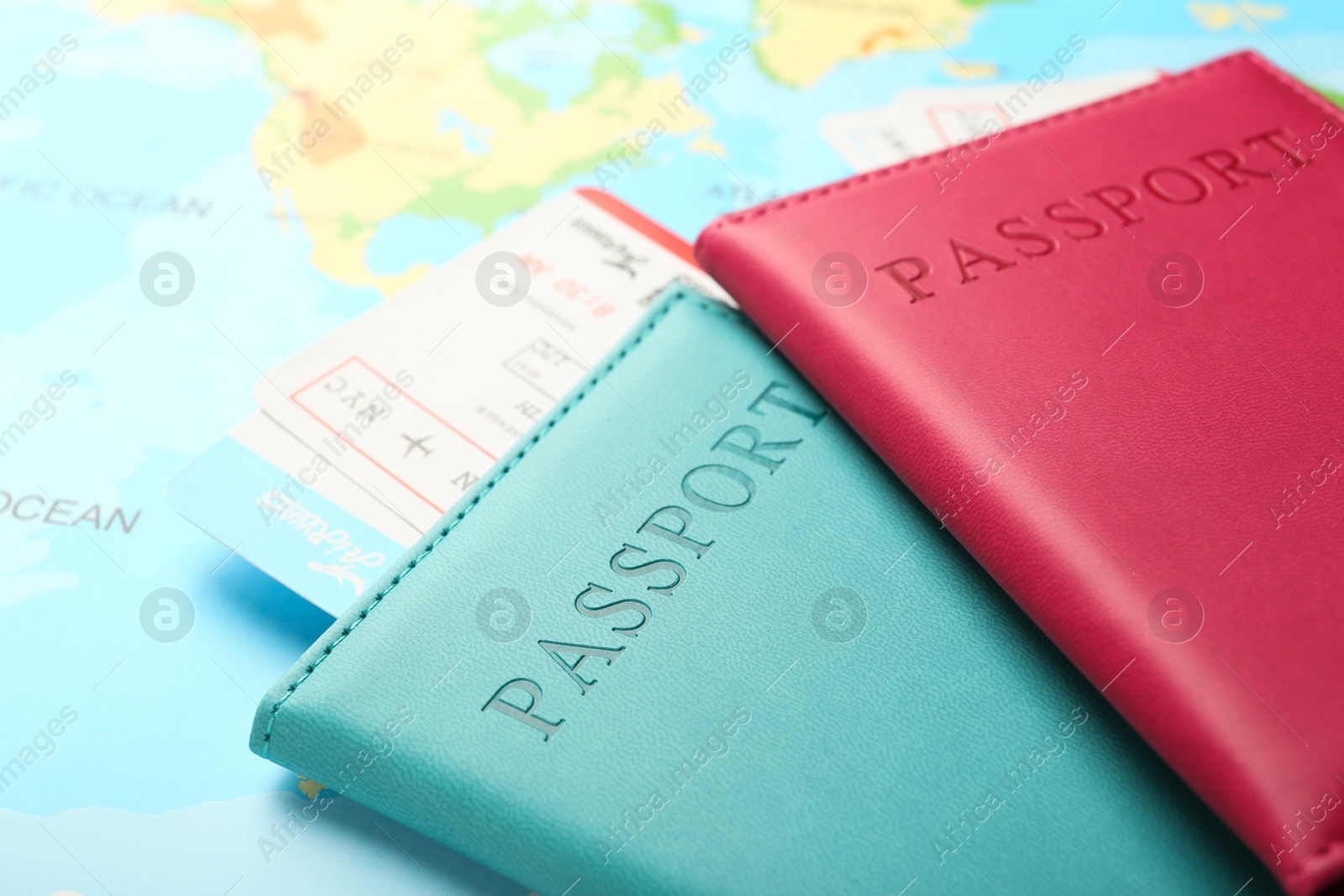 Photo of Passports in color covers and flight tickets on world map, closeup