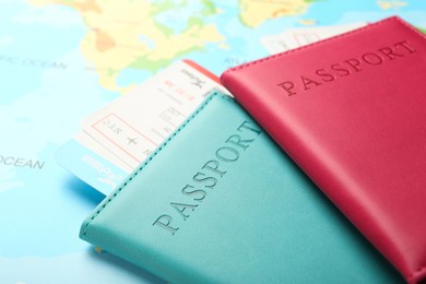 Photo of Passports in color covers and flight tickets on world map, closeup