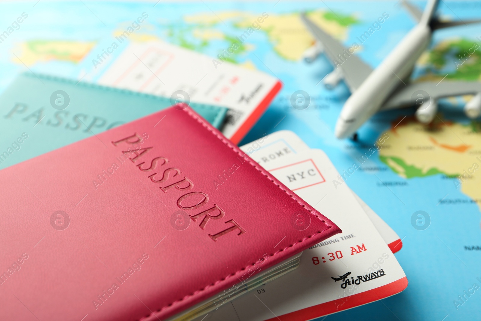 Photo of Passports in color covers, flight tickets and plane model on world map, closeup