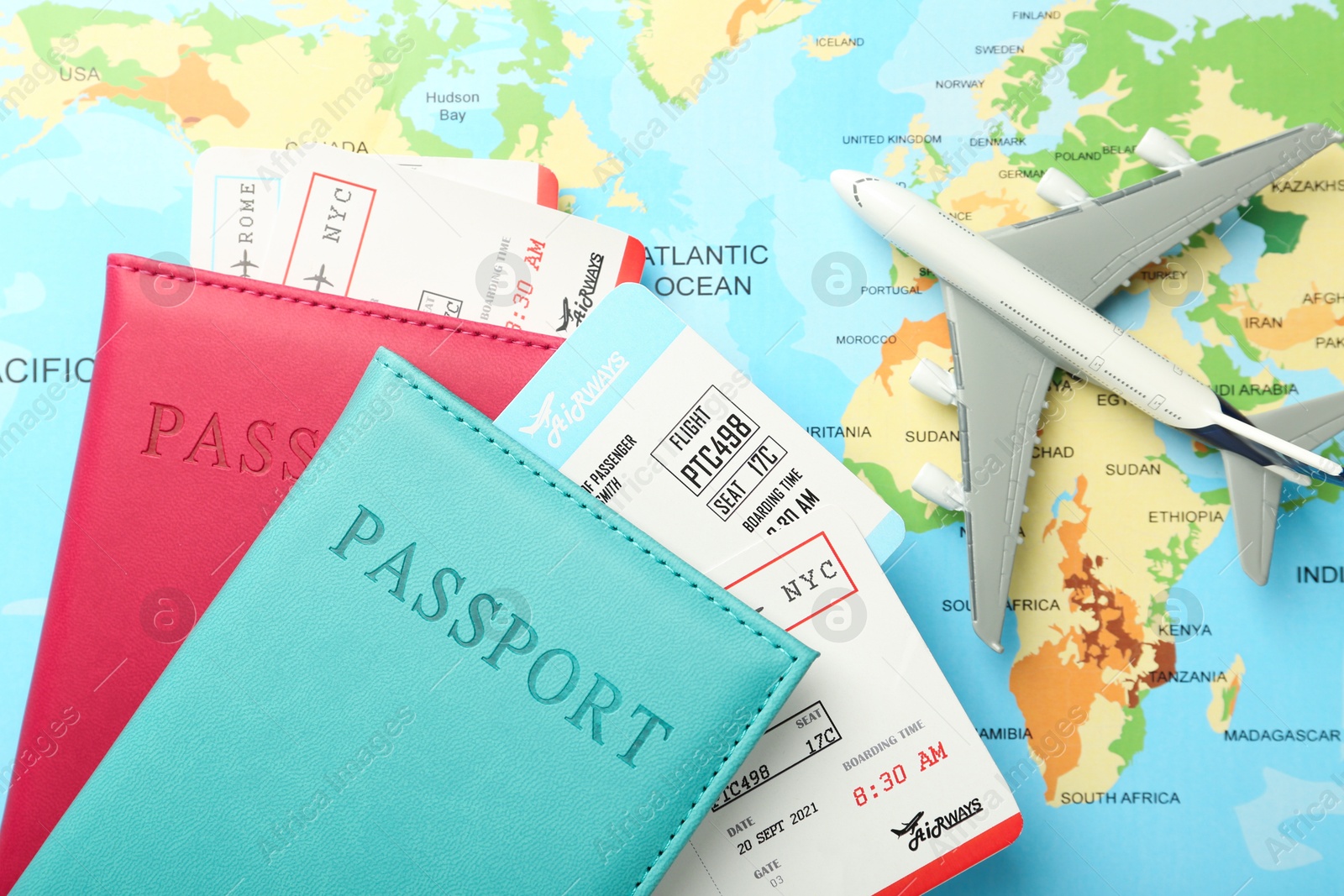 Photo of Passports in color covers, flight tickets and plane model on world map, flat lay