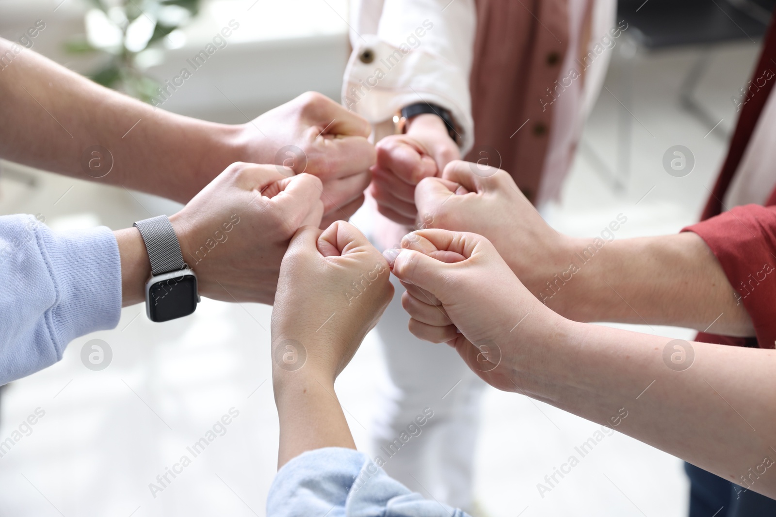 Photo of Unity concept. People holding fists together indoors, closeup