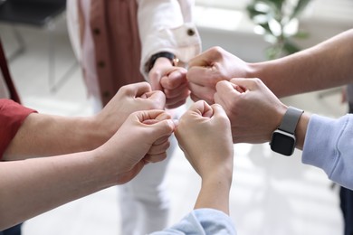 Photo of Unity concept. People holding fists together indoors, closeup