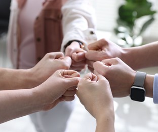 Photo of Unity concept. People holding fists together indoors, closeup