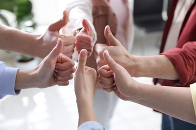 Photo of Unity concept. People showing thumbs up indoors, closeup