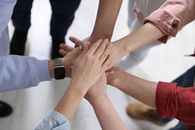 Photo of Unity concept. People holding hands together indoors, above view