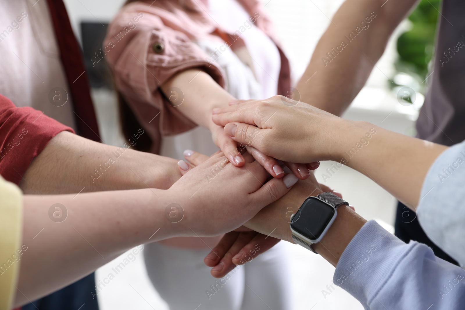 Photo of Unity concept. People holding hands together indoors, closeup