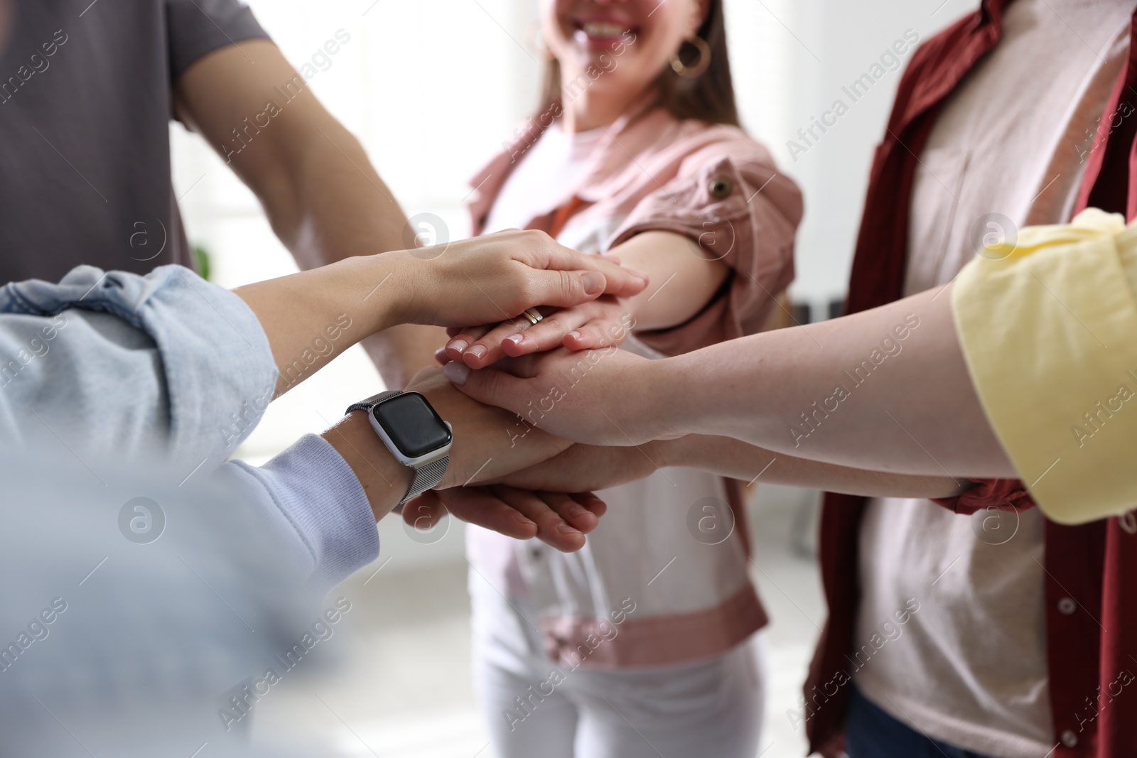 Photo of Unity concept. People holding hands together indoors, closeup