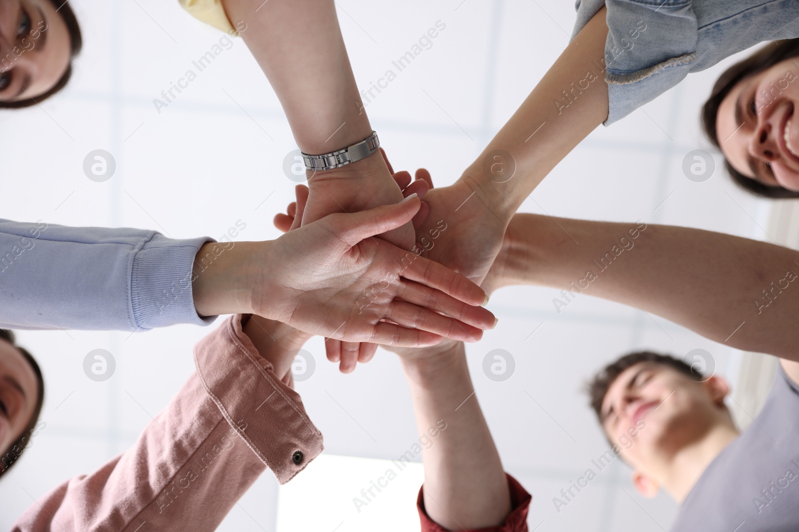 Photo of Unity concept. People holding hands together indoors, bottom view