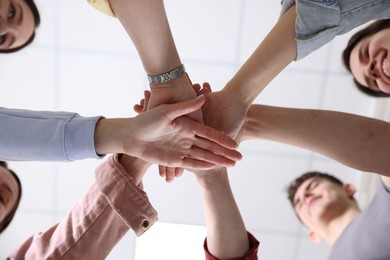 Unity concept. People holding hands together indoors, bottom view