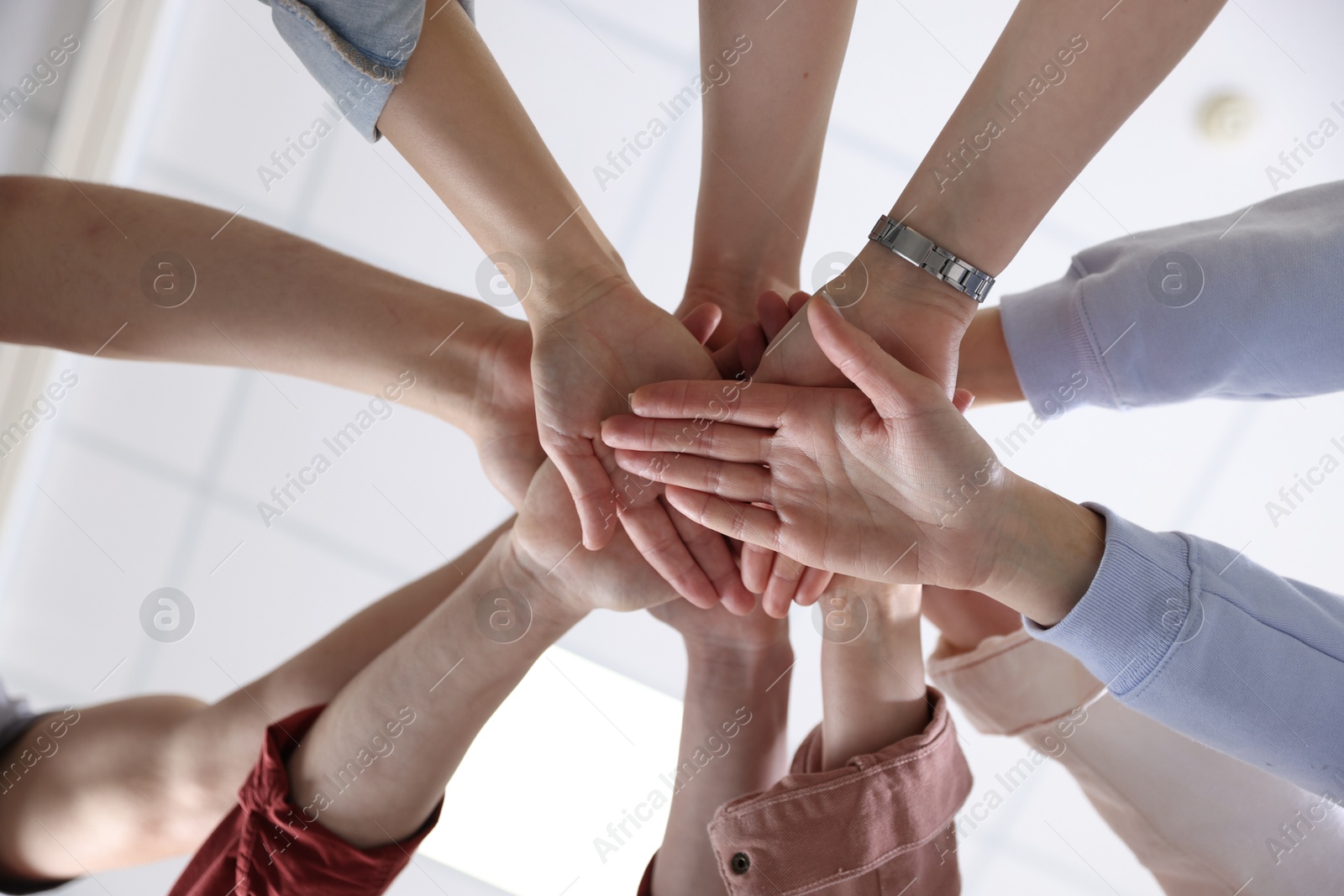 Photo of Unity concept. People holding hands together indoors, bottom view