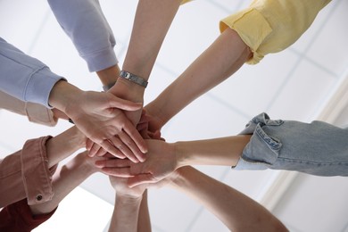 Photo of Unity concept. People holding hands together indoors, bottom view