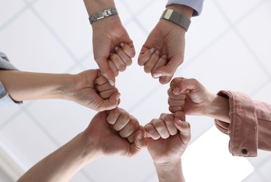 Photo of Unity concept. People holding fists together indoors, bottom view