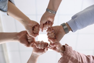 Photo of Unity concept. People holding fists together indoors, bottom view